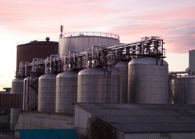 A refinery with large stainless steel storage tanks during sunset, showcasing industrial infrastructure.